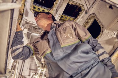 Havacılık garajında uçak altında çalışan bir tamirci.