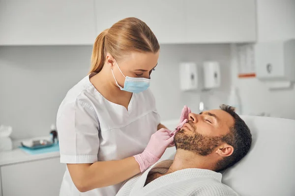 Handsome young man receiving cosmetic injection at wellness clinic — Stock Photo, Image