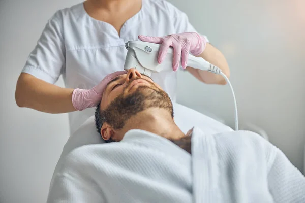 Esteticista feminina tratando a pele masculina com dispositivo laser — Fotografia de Stock