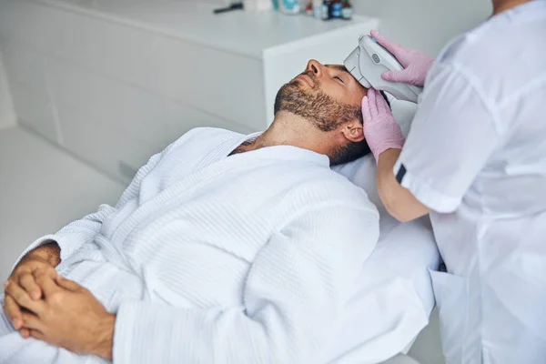 Female doctor esthetician treating male skin with laser device — Stock Photo, Image