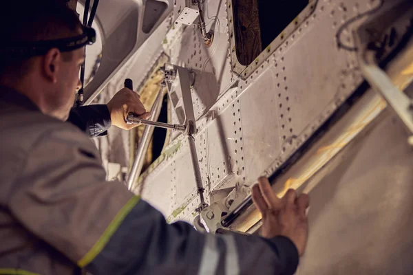 Bakım teknisyeni elinde havacılık teçhizatıyla uçakta çalışıyor.