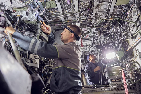 Engineers working with aircraft in repair hangar