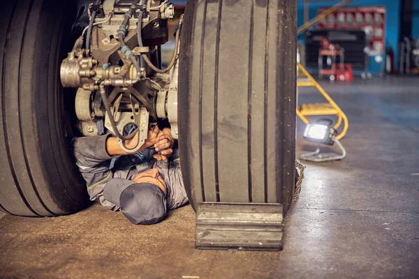 Man is working on airplane under wheels