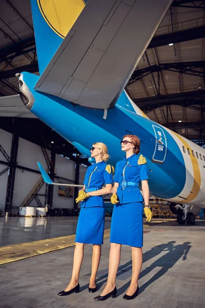 Mulheres elegantes e elegantes aeromoças posando na câmera fotográfica ao ar livre no aeroporto — Fotografia de Stock