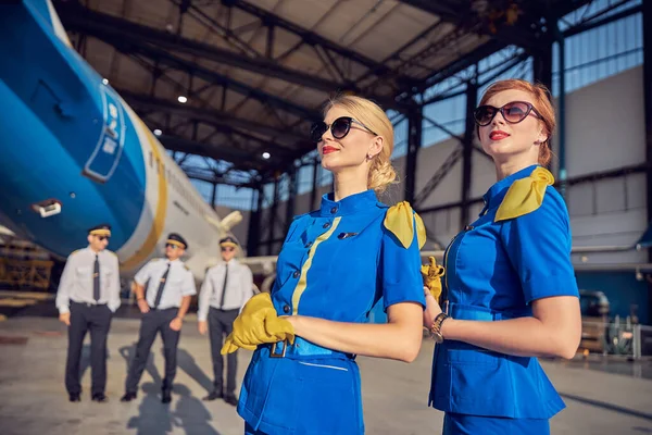 Elegante azafata en guantes de cuero y gafas de sol mirando al cielo — Foto de Stock