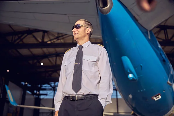 Sorrindo homem bonito de pé perto do hangar de aviação — Fotografia de Stock