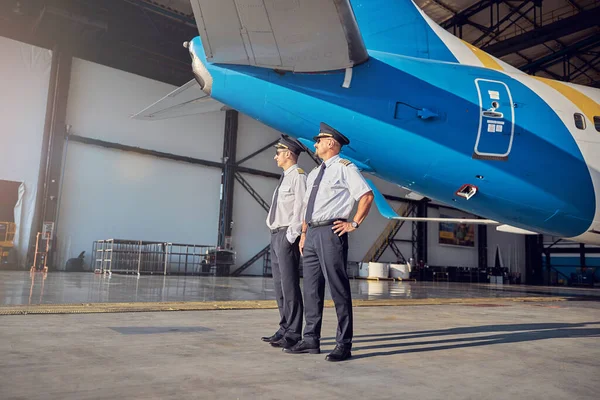 Guapo caucásico hombres en pilotos sombreros mirando al lado en el aire libre en el día soleado — Foto de Stock