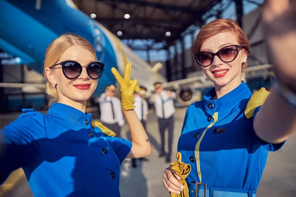 Women air hostesses gesturing at the photo camera while spending time in the outdoors — Stock Photo, Image