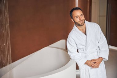 Sağlık merkezinde küvetin yanında duran yakışıklı genç adam.