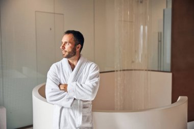 Sakallı genç adam sağlık merkezinde duruyor.