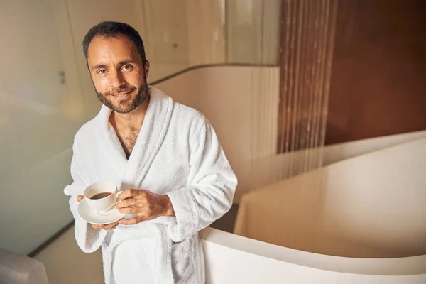 Jovem bonito com café em pé no salão de spa — Fotografia de Stock