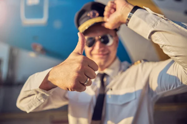 Pilot w białej koszuli trzyma kapelusz, podczas gdy inna ręka gestykuluje na zewnątrz — Zdjęcie stockowe