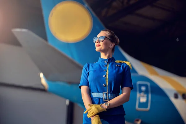 Encantadora mulher aeromoça de pé no hangar no aeroporto — Fotografia de Stock