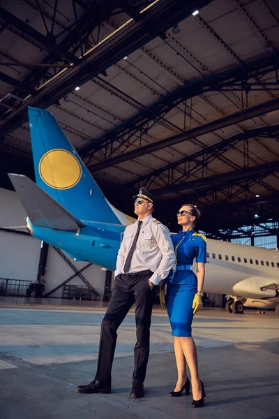 Equipe de voo amigável feliz em pé no hangar no aeroporto — Fotografia de Stock