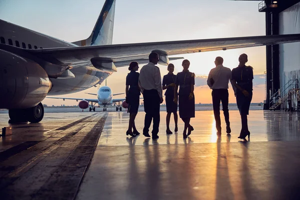 Unrecognizable people standing near the aircraft in the aviation hangar — Stock Photo, Image