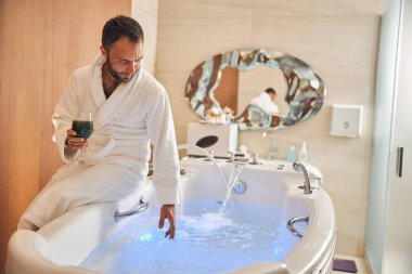 Küvetin kenarında oturan yakışıklı genç adam.