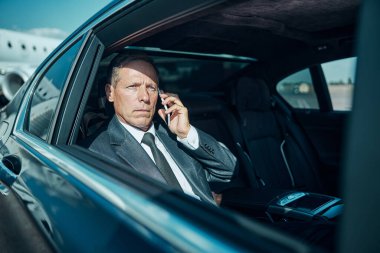 İş adamı havaalanında akıllı telefondan konuşuyor.