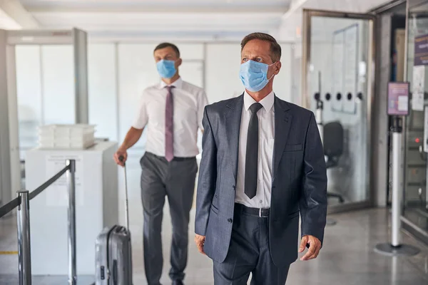 Zakenman die met bodyguard op het vliegveld loopt tijdens quarantaine — Stockfoto