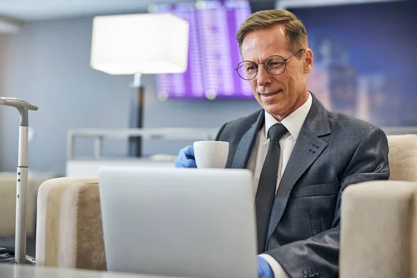 空港ラウンジでノートパソコンでリラックスした笑顔のビジネスマン — ストック写真