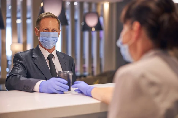 Glimlachende man met masker en handschoenen die koffie kopen — Stockfoto