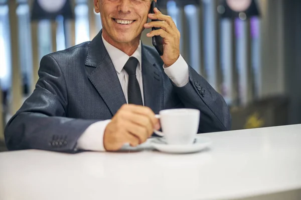 笑顔のビジネスマンがバーでスマートフォンで話している — ストック写真