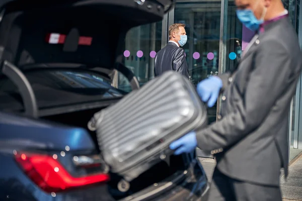 Élégant conducteur emballant les bagages du patron dans la voiture à l'aéroport — Photo