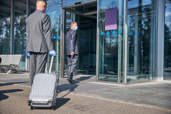 Geschäftsmann wird während Pandemie am Flughafen vom Fahrer unterstützt — Stockfoto