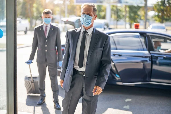 Twee elegante mannen met maskers die het vliegveld betreden — Stockfoto