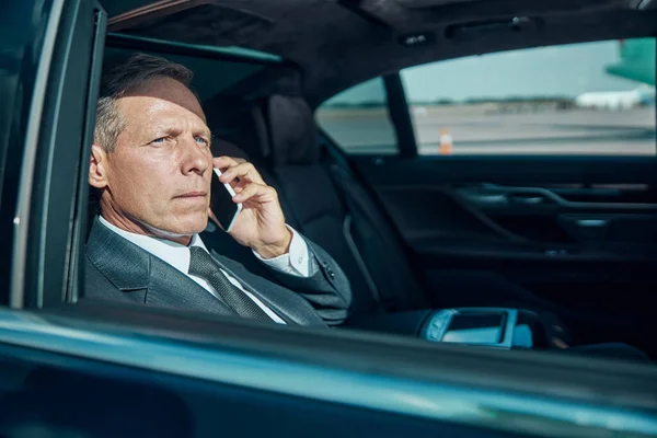 Biznesmen rozmawiający przez telefon komórkowy w luksusowym samochodzie — Zdjęcie stockowe