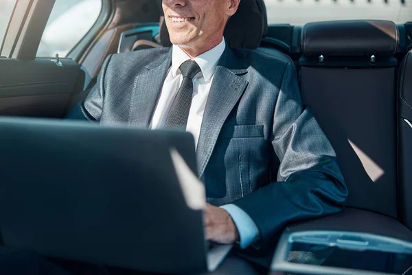 Wesoły elegancki mężczyzna z laptopem w samochodzie — Zdjęcie stockowe