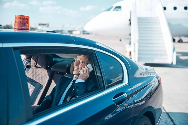 Sorridente uomo elegante che fa chiamata durante il trasferimento dall'aereo — Foto Stock