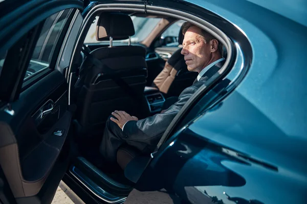 Handsome mature businessman sitting in comfortable car — Stock Photo, Image