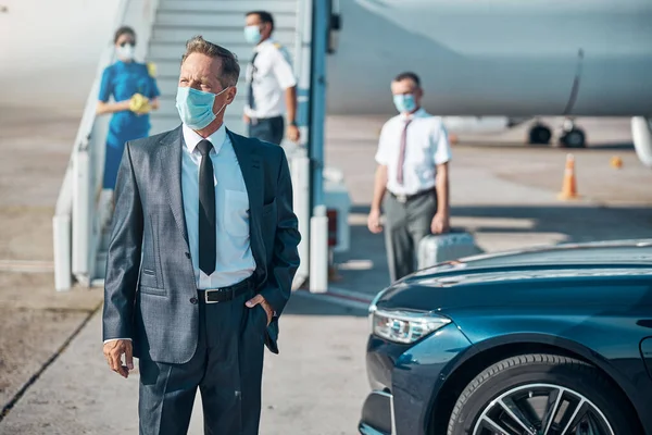 Elegante man met masker op op reis met het vliegtuig — Stockfoto