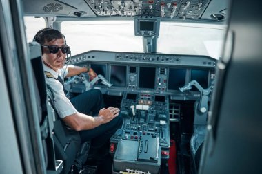 Gülümseyen yakışıklı pilot uçak kokpitinde oturuyor.