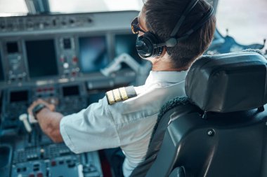 Erkek pilot güneşli bir günde yolcu uçağı uçuruyor.