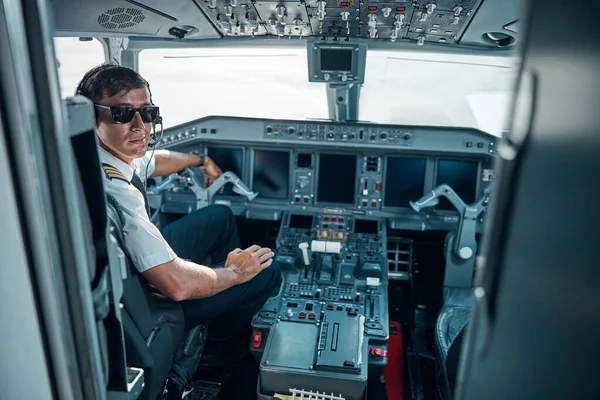 Piloto bonito sorridente sentado no cockpit do avião — Fotografia de Stock