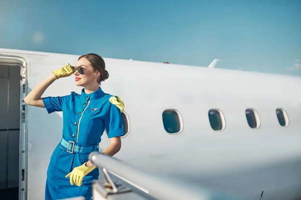 Весела красива стюардеса зустрічає пасажирів у сонячний день — стокове фото