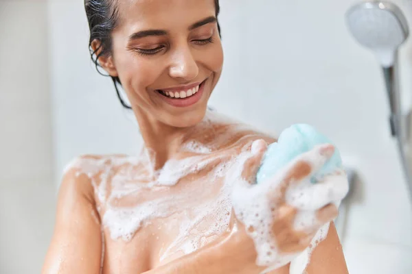 Fröhliche junge Frau benutzt Peeling-Luffa beim Duschen — Stockfoto