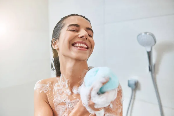 Lächelnde junge Frau wäscht Körper mit Badeschlauch — Stockfoto