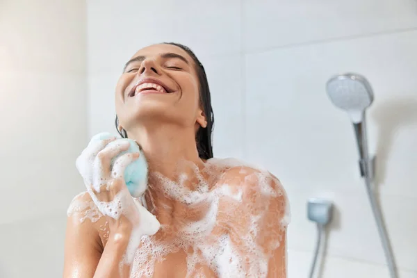 Fröhliche junge Frau wäscht ihren Körper mit Badeschlauch — Stockfoto