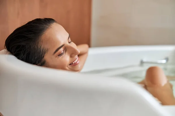 Joyeux jeune femme relaxant dans la baignoire à la maison — Photo