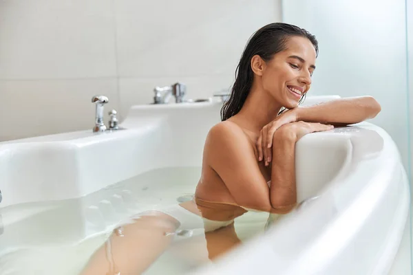 Charmig ung kvinna ligger i vitt badkar hemma — Stockfoto