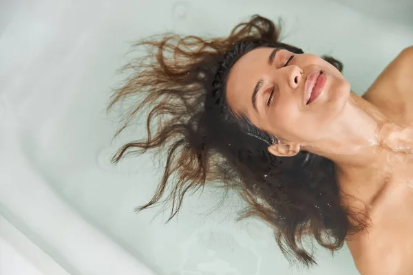 Gyönyörű fiatal nő fekszik a vízben a fürdőkádban — Stock Fotó