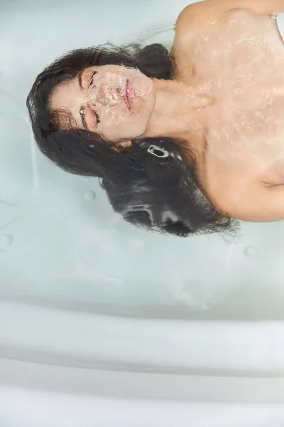Красивая молодая женщина, лежащая под водой в ванной — стоковое фото
