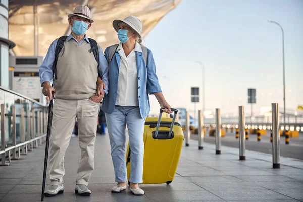 Idős házaspár arcmaszkban a reptéren. — Stock Fotó