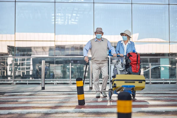 Two aged travelers walking across the street — Stock Photo, Image