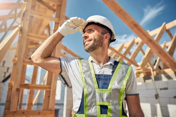 Joyful jovem construtor olhando para cima no céu azul — Fotografia de Stock