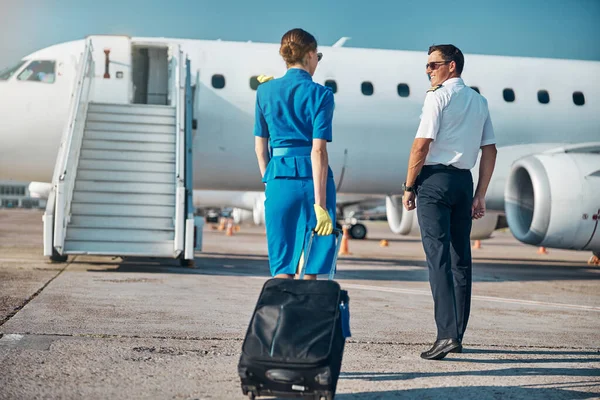 Neşeli ekip bavulla uçağa yürüyor.