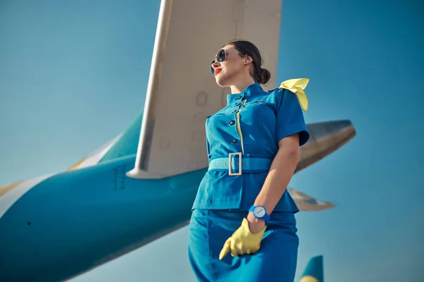 Счастливая милая стюардесса возле пассажирского самолета на открытом воздухе — стоковое фото