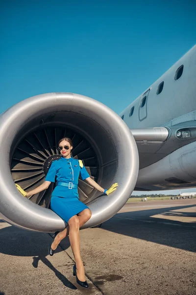 Veselá krásná letuška odpočívající v blízkosti osobního letadla — Stock fotografie